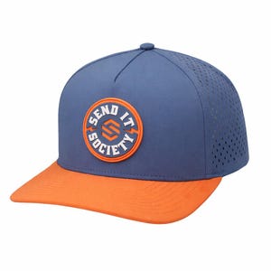Può includere: Un cappellino da baseball blu con visiera arancione e una toppa circolare arancione sul davanti. La toppa presenta la scritta "SEND IT SOCIETY" in lettere bianche attorno a un logo geometrico arancione. I pannelli posteriori sono traforati.