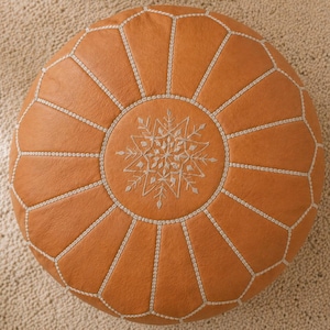 May include: A white ceramic mug with a black handle and the text "But First, Coffee" in a bold, black font. The mug is set against a blurred background, suggesting a cozy setting.