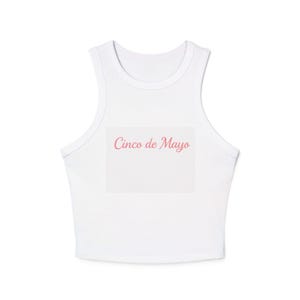 Pode incluir: Top curto branco com decote redondo e um design retangular no centro. O design apresenta o texto "Cinco de Mayo" em rosa, com uma fonte cursiva. O top é sem mangas.