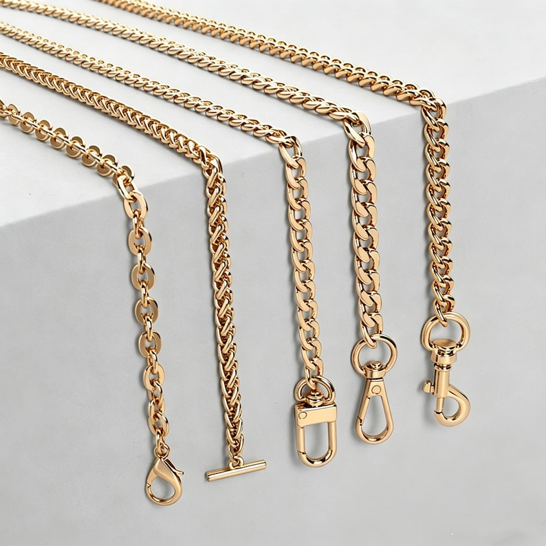 May include: Five gold-toned metal chains of varying styles, including flat oval links, a braided wheat chain, and three curb chains. Each chain features a distinct metal clasp or toggle end, such as a lobster claw, a T-bar, or a swivel snap hook.