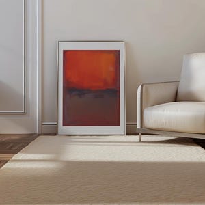 Peut inclure: Une œuvre d'art murale rectangulaire encadrée présentant une composition abstraite avec une section supérieure orange vif et une section inférieure brun foncé et sourd, séparées par une ligne de transition horizontale douce.