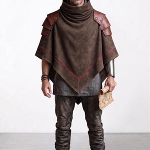 May include: A brown poncho with a high cowl neck, layered leather shoulder pauldrons, and a thin red horizontal stripe. The outfit includes a grey tunic, dark brown trousers, a metallic forearm bracer, and brown leather boots, holding a scroll.