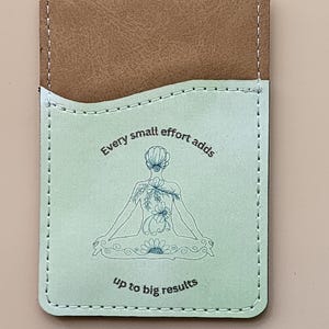 May include: A light green leather card holder with a white stitched border. The card holder features a line drawing of a person sitting in a yoga pose with flowers and the text "Every small effort adds up to big results".