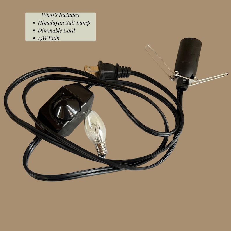 May include: A black electrical cord with a dimmable switch, a light bulb socket with metal tension clips, and a 15W light bulb. Text in the image reads: What's Included, Himalayan Salt Lamp, Dimmable Cord, 15W Bulb. The cord has a standard two-prong plug.