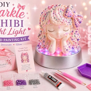 May include: A DIY Chibi night light diamond painting kit. The kit includes a light-up figurine with a multi-color LED base, pink gems, purple gems, and gray gems. The kit also includes a box with a pink bow and the text "PearlBloomStudioCo".