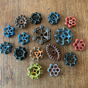 May include: Assortment of vintage metal water valve handles in various colors and designs. The handles are in a star, flower, and round shape.
