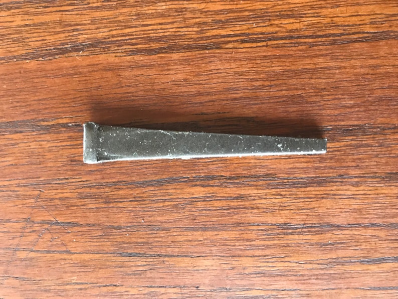 May include: A silver metal nail with a pointed tip and a flat head.