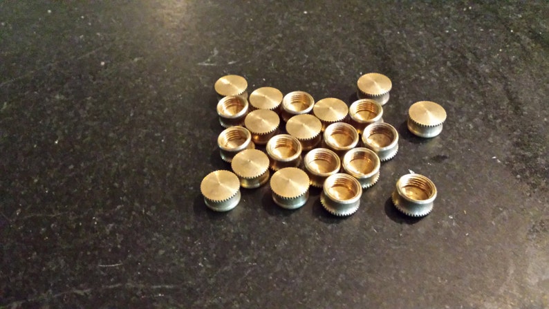 May include: A group of 20 gold-colored metal caps, likely for use with plumbing or other household applications.