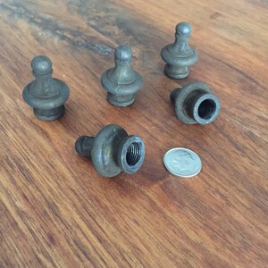 May include: A collection of five antique metal finials with a dark, aged finish. Each finial has a bulbous base and a rounded top. A dime is included for size reference.