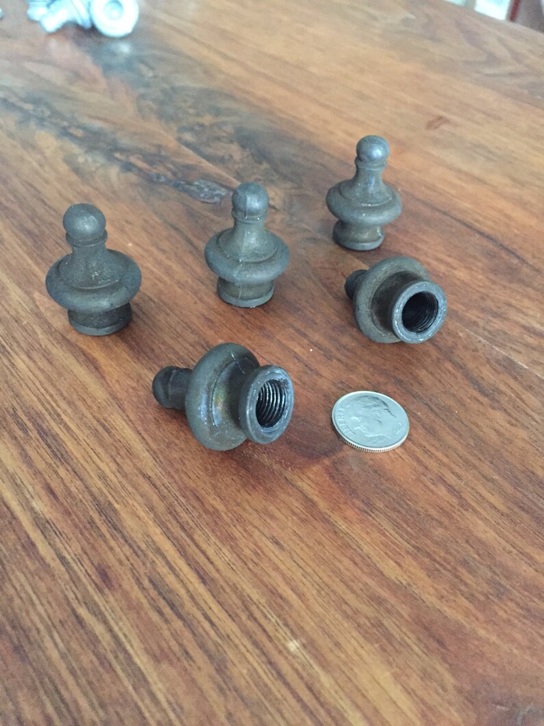 May include: A collection of five antique metal finials with a dark, aged finish. Each finial has a bulbous base and a rounded top. A dime is included for size reference.