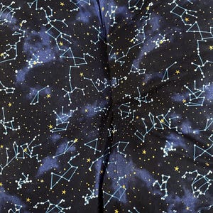 Può includere: Tessuto blu scuro con un motivo celeste con costellazioni bianche e gialle. Il design include stelle collegate e punti sparsi, che ricordano un cielo notturno. Il tessuto ha un aspetto morbido e leggermente strutturato.