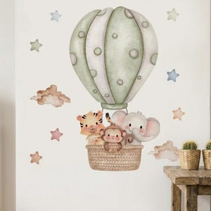 May include: Watercolor illustration of a hot air balloon with a basket carrying a tiger, monkey, and elephant. The balloon is green and white, with stars and clouds scattered around the image. A charming nursery wall decal.