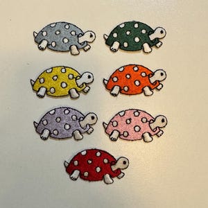 May include: Six embroidered iron-on patches of turtles with white polka dots. The turtles are in various colors: gray, green, yellow, orange, purple, and red.