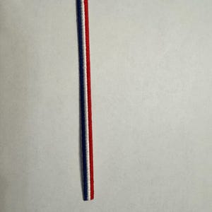May include: A thin red, white, and blue ribbon.