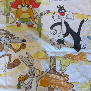 Könnte beinhalten: Weißes Bettlaken mit Zeichentrickfiguren wie Yosemite Sam, Sylvester the Cat, Wile E. Coyote, Bugs Bunny und Tweety. Das Laken hat einen Wüstenlandschaftshintergrund und den Text "WARNER BROS. INC. 1977".