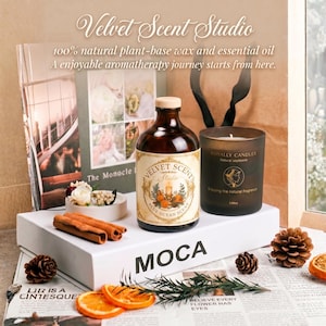 May include: Aromatherapy set with a brown glass bottle and a candle in a dark glass. The bottle is labelled "Velvet Scent Studio." The set includes cinnamon sticks, pine cones, and dried orange slices, arranged on a white box.