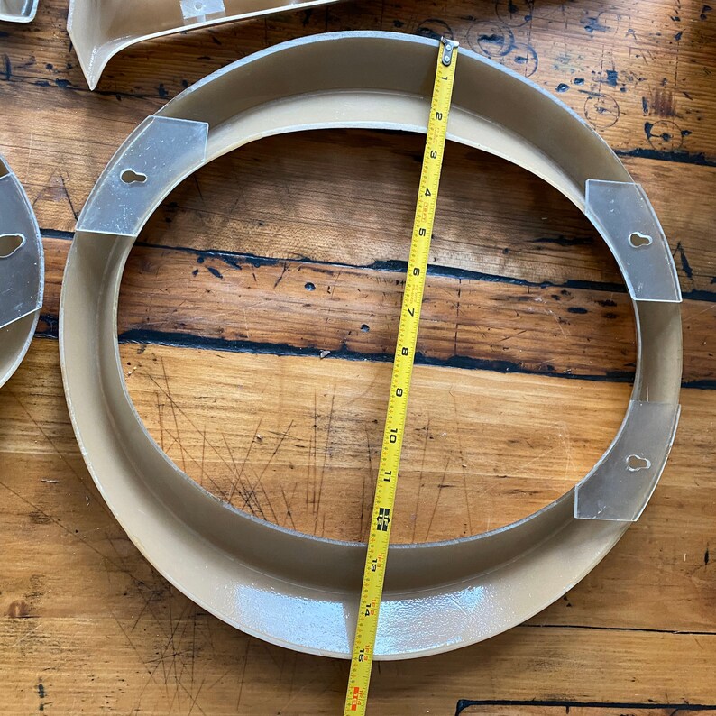 May include: A beige-colored, round, decorative frame with a clear plastic insert. The frame is 12 inches in diameter and has a smooth, glossy finish.