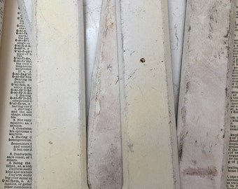 Può includere: Primo piano di una lettera U dipinta di bianco. La lettera è realizzata in materiale spesso e testurizzato e sembra far parte di un set di lettere più grande. La lettera è appoggiata su una pagina di un libro con testo visibile sullo sfondo.