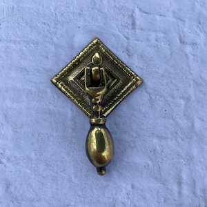 Op de afbeelding: Een gouden metalen kastknop met een ruitvormige basis en een traanvormig handvat.