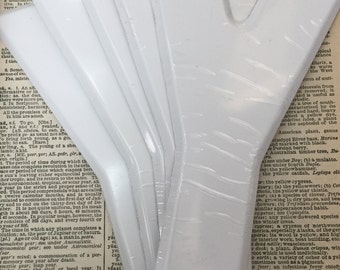 Può includere: Primo piano di sei oggetti bianchi, rettangolari, vuoti, simili alla carta, impilati uno sopra l'altro. Gli oggetti sono leggermente curvi e hanno una superficie liscia e lucida.