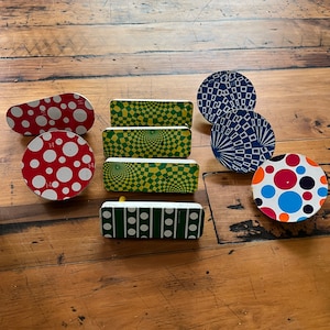 May include: A set of eight colorful, round and rectangular decorative wall hooks with geometric patterns. The hooks feature a variety of designs, including polka dots, squares, and circles. The hooks are made of metal and have a shiny finish.