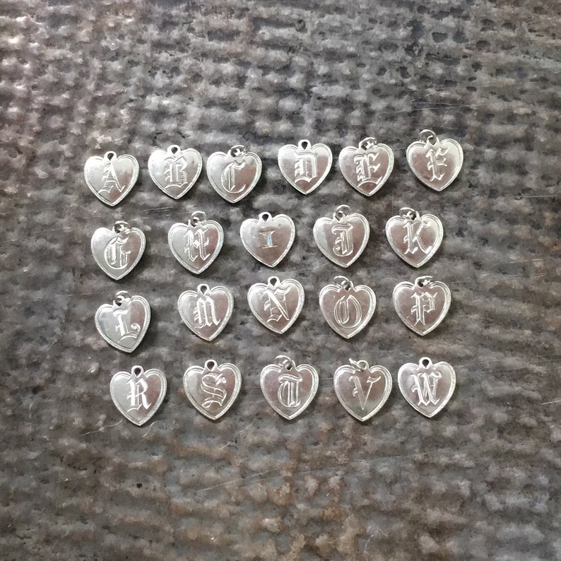 May include: A set of 26 silver heart-shaped charms, each featuring a different letter of the alphabet in a gothic font.