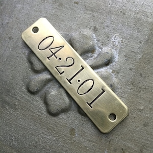 Peut inclure: Une étiquette en laiton aux coins arrondis et deux trous. L'étiquette est gravée avec la date "04.21.01".