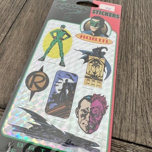 Peut inclure: Une feuille d'autocollants Batman avec des personnages comme Robin, l'&eacute;nigme, Double-Face et Batman. Les autocollants sont holographiques et ont un prix de 99 centimes.