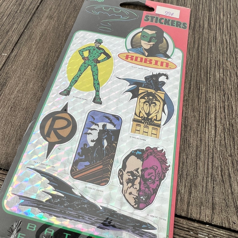 Peut inclure: Une feuille d'autocollants Batman avec des personnages comme Robin, l'&eacute;nigme, Double-Face et Batman. Les autocollants sont holographiques et ont un prix de 99 centimes.