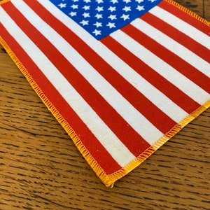 Pu&ograve; includere: Un piccolo patch di bandiera americana con strisce rosse e bianche e un campo blu di stelle. La bandiera &egrave; cucita con un bordo giallo.