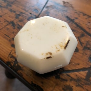 Peut inclure: Bouton de porte en verre octogonal blanc avec des taches brunes.