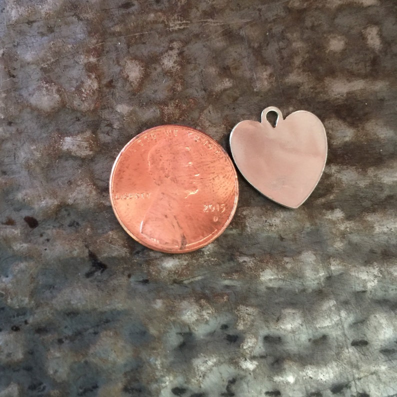May include: A silver heart-shaped charm pendant, approximately the size of a UK penny.