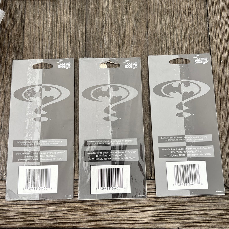 Peut inclure: Trois emballages de cartes blanches pour des d&eacute;sodorisants avec le logo de Batman. Au dos de l'emballage, on peut lire "BATMAN and all related elements are the property of DC Comics &copy; 1992. All rights reserved." et "Manufactured under license by Mello Smello InterNatural Designs Inc. 5100 Highway 169 N - Minneapolis, MN 55428".
