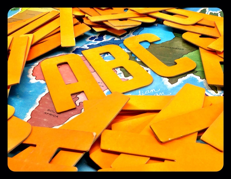 May include: A close-up of a pile of yellow cardboard letters that spell out "ABC". The letters are arranged on a map of the world with the text "Afghanistan" and "South Africa" visible.