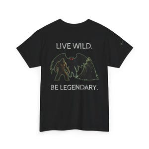 May include: Black t-shirt featuring a graphic of cryptids, including Bigfoot, a winged creature, and a cloaked figure. The text "LIVE WILD. BE LEGENDARY." is printed in white above and below the graphic. The shirt is a crew neck.