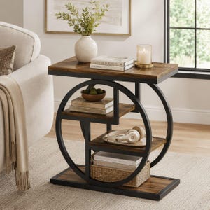 May include: A rectangular side table with a dark wood grain finish and a black metal circular frame. The table features three tiers of shelving, providing storage space for books, a small wooden bowl, headphones, and a woven basket.