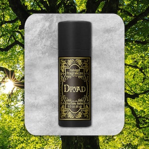 May include: A black tube with a gold label that reads "Fabled Fragrances Dryad Parfum Balm 0.5 oz (15 g)". The label has a decorative floral design.