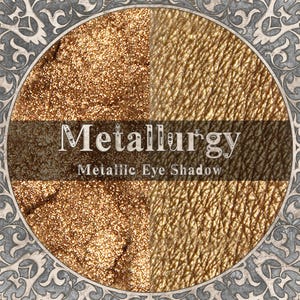 May include: A circular display of Metallurgy metallic eye shadow featuring a split-screen view of a loose, shimmering gold powder on the left and a smooth, applied gold pigment swatch on the right, framed by an ornate, grey filigree border.