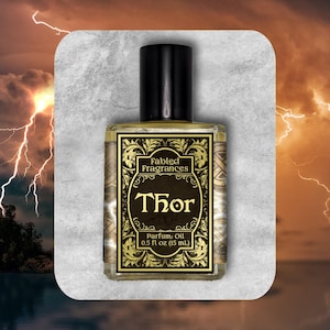 Könnte beinhalten: Eine klare Glasflasche mit Parfümöl und einem schwarzen Verschluss. Das Etikett zeigt goldene, verzierte Ränder auf schwarzem Grund mit dem Text Fabled Fragrances, Thor und 15 mL (0,5 fl oz) in goldener Serifenschrift auf der Vorderseite.