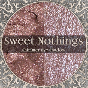 Pode incluir: Um r&oacute;tulo de produto cosm&eacute;tico circular com o texto Sweet Nothings Shimmer Eye Shadow. A imagem mostra uma vista dividida de um p&oacute; cintilante de ouro rosa met&aacute;lico e uma amostra do mesmo produto aplicada em pele texturizada.