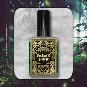 Könnte beinhalten: Eine Parfümflasche mit schwarzem Verschluss und einem Etikett mit der Aufschrift "Fabled Fragrances Enchanted Forest Eau de Parfum 1 fl oz (30 ml)". Das Etikett hat einen grünen Hintergrund mit goldenen Verzierungen.