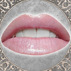 以下が含まれることがあります： ピンクの口紅と光沢のある仕上げを施した唇のクローズアップ。唇はわずかに開いており、白い歯が並んでいます。