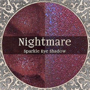 May include: A circular eyeshadow compact with four sections of shimmering, dark red and purple shades. The text "Nightmare Sparkle Eye Shadow" is displayed in a dark brown banner across the center of the compact. The compact is set within a decorative, ornate frame.
