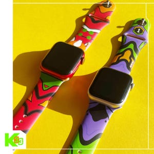 May include: Two smartwatches with colorful patterned bands. One watch has a red case and the other has a silver case. The bands feature a mix of red, green, purple, and yellow designs. The watches are displayed on a bright yellow surface.