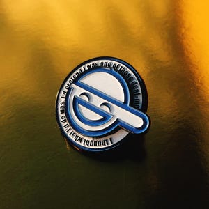 Puede incluir: Un pin redondo de esmalte con un diseño blanco y azul. El pin presenta el texto "I thought what I'd do was I'd pretend I was one of those deaf-mute". El pin tiene un diseño de cara sonriente.