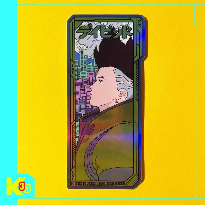 May include: A holographic sticker with a futuristic design, featuring a profile of a person with a unique hairstyle. The sticker has Japanese text at the top and a cityscape in the background, framed by a green and gold border. The background is yellow.