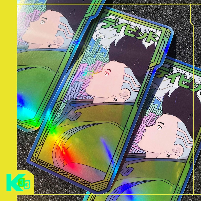 May include: Holographic trading cards with a futuristic anime character in a green jacket and a cityscape backdrop. The cards have Japanese text and a rainbow sheen, with a yellow and black border.