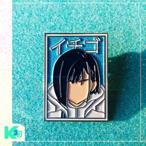 May include: A rectangular enamel pin featuring an anime character with black hair and a white hoodie. The character's face is partially visible. Japanese text is at the top. The pin has a blue and white color scheme.