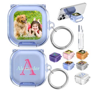 Può includere: Una custodia protettiva quadrata e traslucida color azzurro per auricolari wireless con un anello in metallo. Una custodia mostra la foto di un cane e di un bambino con la parola Custom, mentre un'altra mostra una grande lettera A rosa e Alexander.