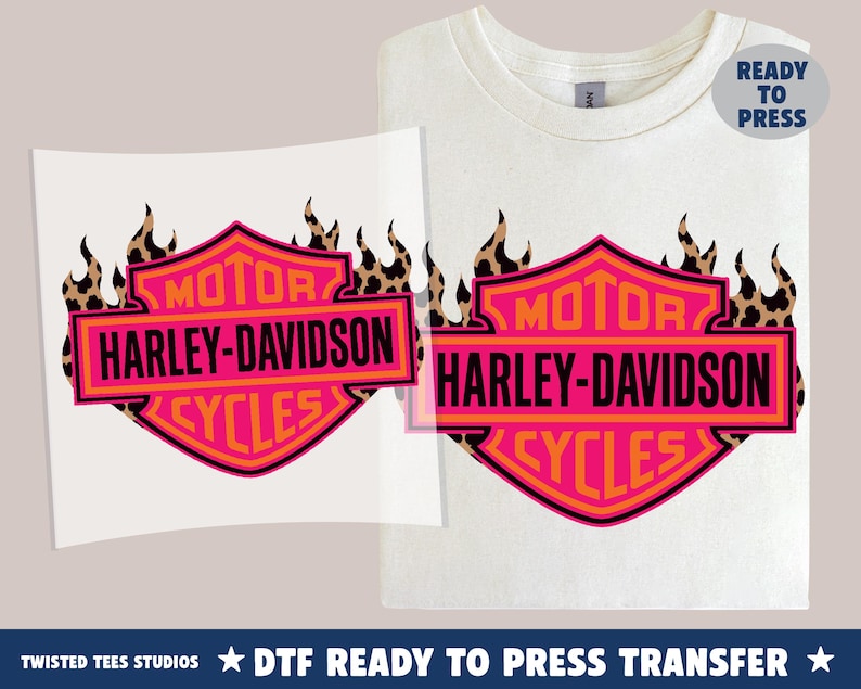 May include: A white t-shirt and a separate transfer sheet both featuring a pink and orange Harley-Davidson Motor Cycles shield logo with a black leopard print flame design. A blue circular badge in the corner displays the text Ready To Press.